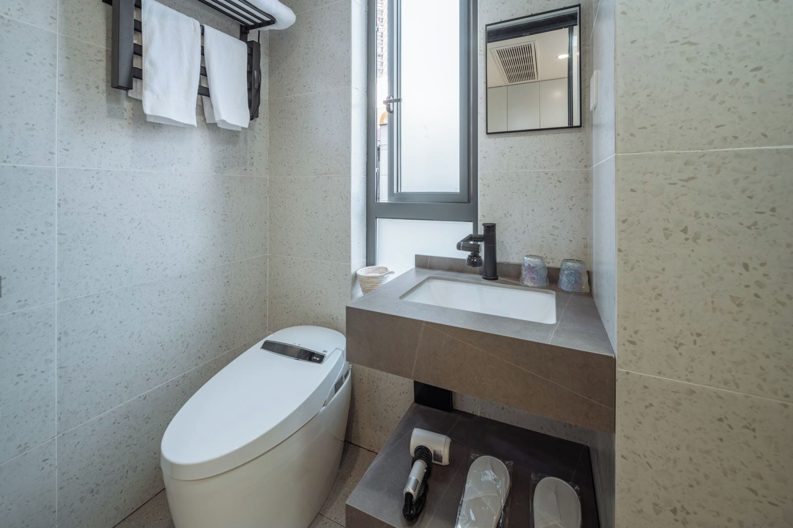 A modern bathroom with a toilet, sink, and mirror.