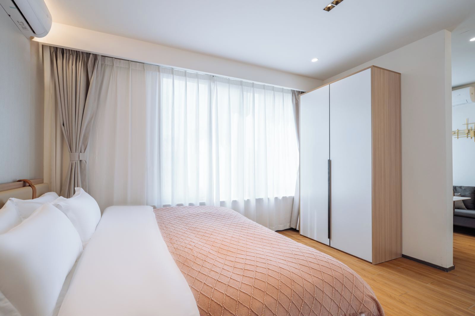 Een moderne hotelkamer met een groot bed, een kledingkast en uitzicht op de stad.