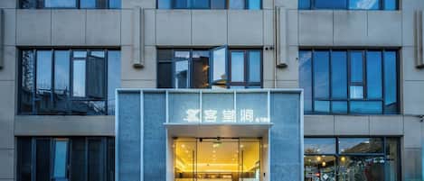 A modern building with a glass entrance and a sign in a foreign language.