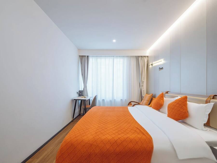 Ein Hotelzimmer mit Bett, Schreibtisch und einem fenster mit Vorhängen.