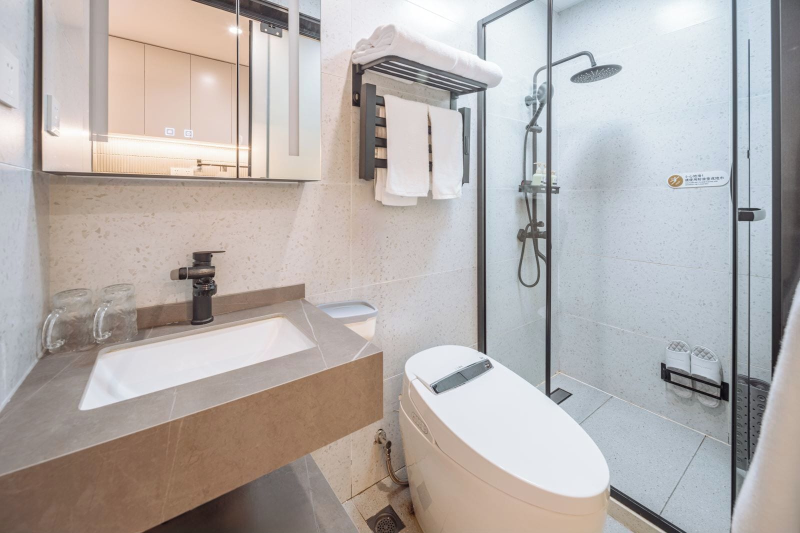 Een moderne badkamer met een glazen douchecabine, een wastafelmeubel met een wastafel en een toilet.
