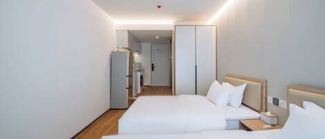 A hotel room with two beds, a wardrobe, a small table, and a washing machine in the background.