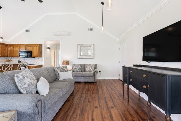A living room with a grey sofa, a black entertainment unit, and wooden flooring.