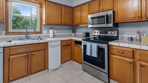 A kitchen with wooden cabinets, a stainless steel microwave, an oven, and a dishwasher.