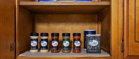 A kitchen with a wooden cabinet containing spice jars and a box of paper towels.