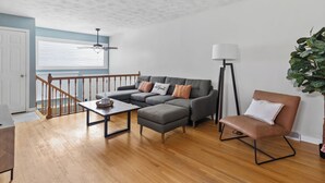 A living room with a grey sectional sofa, a brown armchair, a coffee table, and a floor lamp.