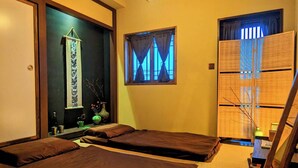 A room with two beds, a window with blue curtains, a mirror, and a traditional Japanese sliding door. - Tainan Kyomachiya Emoh House (Tainan)