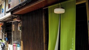 A traditional Japanese building with a wooden exterior, a balcony, and a green curtain with Japanese characters. - Tainan Kyomachiya Emoh House (Tainan)