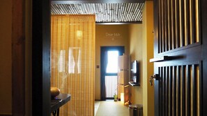 A hotel corridor with a traditional Japanese-style room, a wooden door, and a reception area. - Tainan Kyomachiya Emoh House (Tainan)