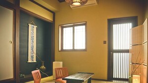 A traditional Japanese room with tatami flooring, a low table, two chairs, a hanging scroll, and a sliding door. - Tainan Kyomachiya Emoh House (Tainan)