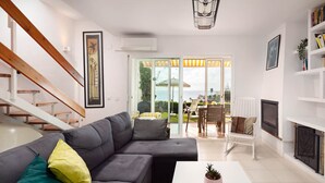 Una sala moderna con un sofá seccional gris, una mesa de centro blanca, una chimenea y una escalera.