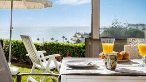 Una mesa con alimentos para el desayuno, vista al mar y un paraguas blanco.