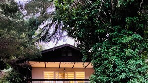 Un bâtiment à deux étages doté d’un balcon, entouré d’une végétation luxuriante.