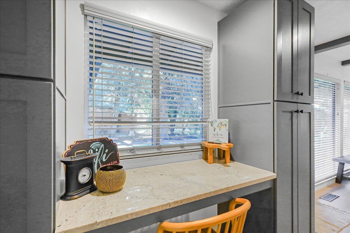 A kitchen with a window, a countertop, a chair, and cabinets.
