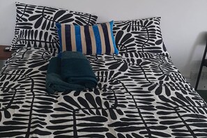 A bed with a leaf-patterned bedspread, a striped pillow, and a folded blanket. - Newport Ensuite, Sleeps 2 near Train Station (Newport)
