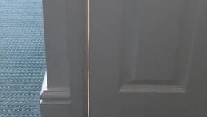 Une porte qui donne sur une pièce dont le sol est recouvert d’une moquette à motifs.