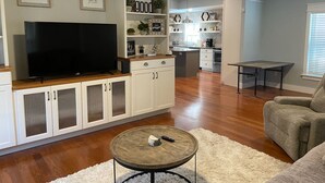 Un soggiorno moderno con una TV a schermo piatto, mobili bianchi e un angolo salotto accogliente.