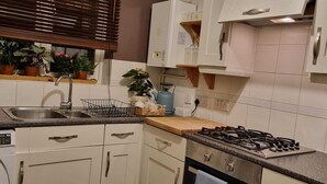 Una cucina con lavatrice integrata, lavello, piano cottura e pensili.