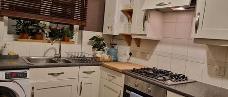 A kitchen with a built-in washing machine, a sink, a stove, and cabinets.