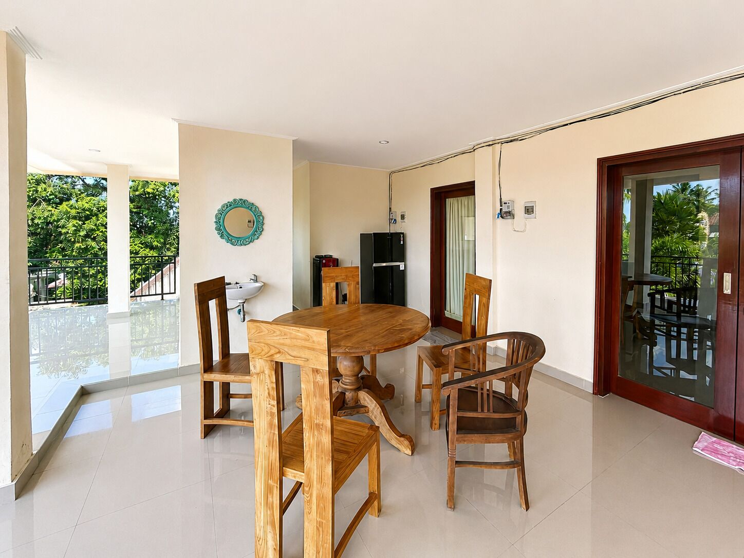 A dining area with a wooden table and chairs, a sink, and a mirror on the wall.