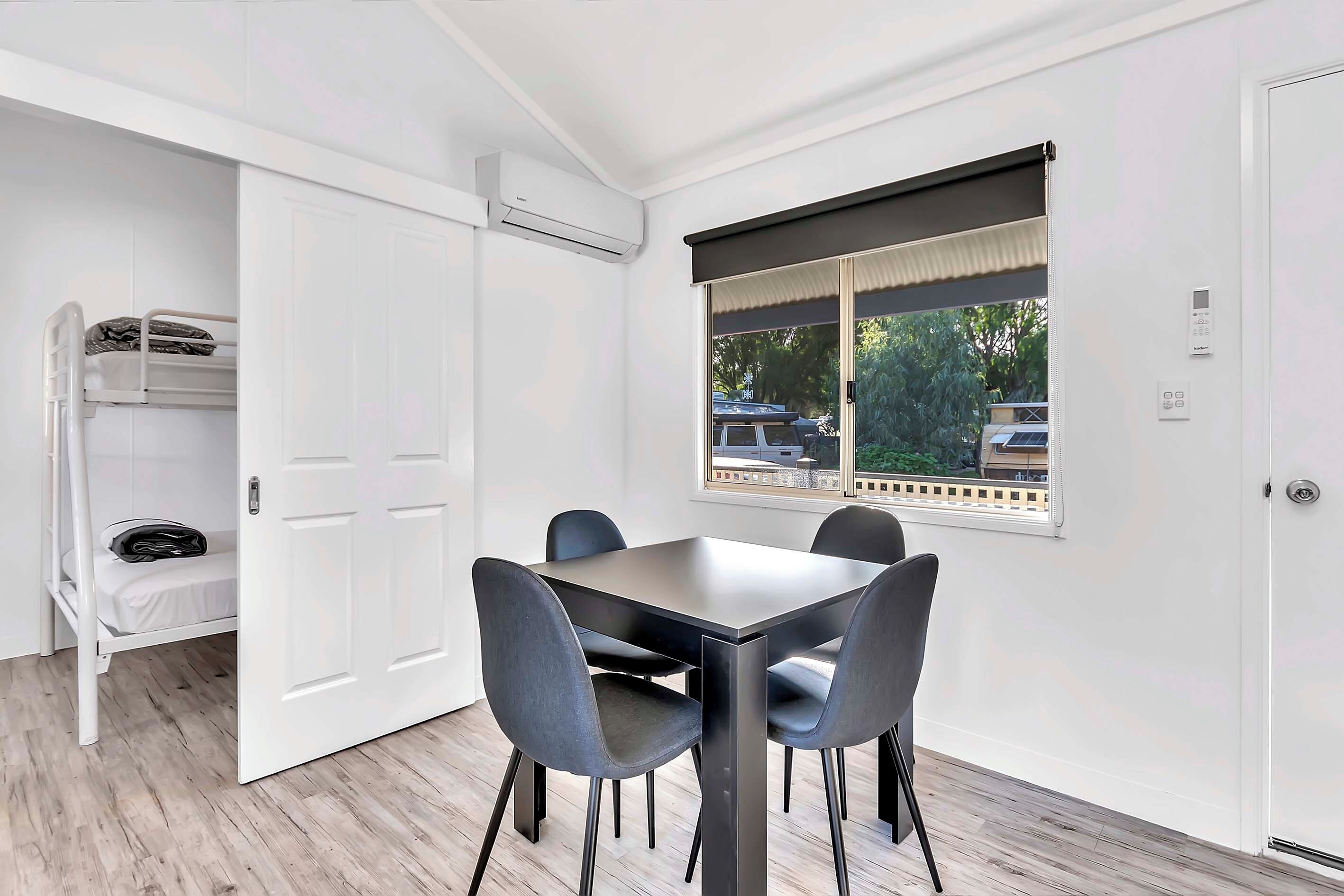 Una habitación con una mesa de comedor, sillas, un ventanal con vistas y una puerta que da a un armario.