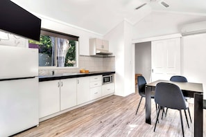 A modern kitchen with white cabinetry, a black countertop, and a window overlooking greenery. - Rockingham Holiday Village (East Rockingham)