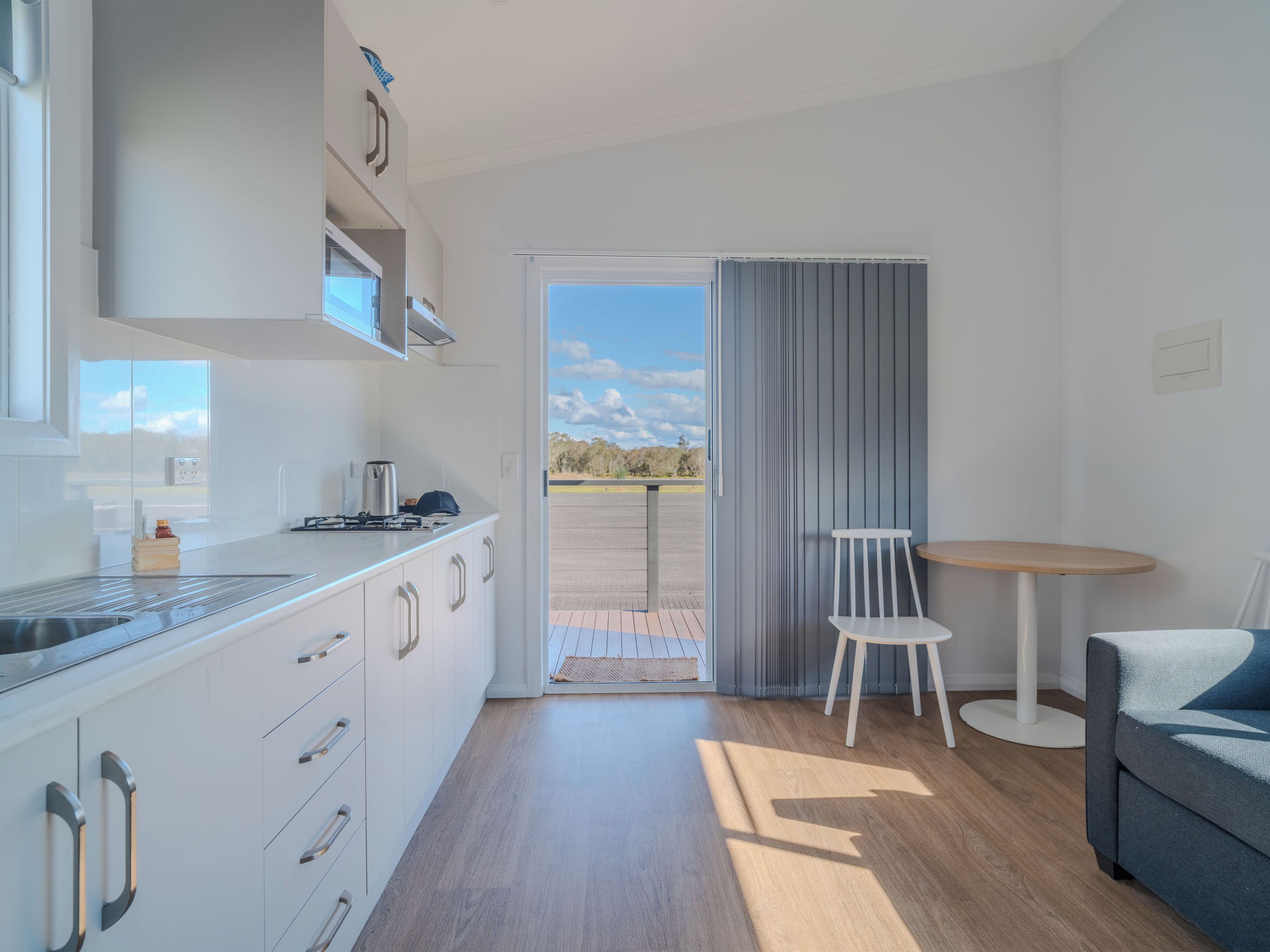 Una cocina moderna con horno integrado, un comedor con mesa y sillas, y vistas al exterior a través de un ventanal.
