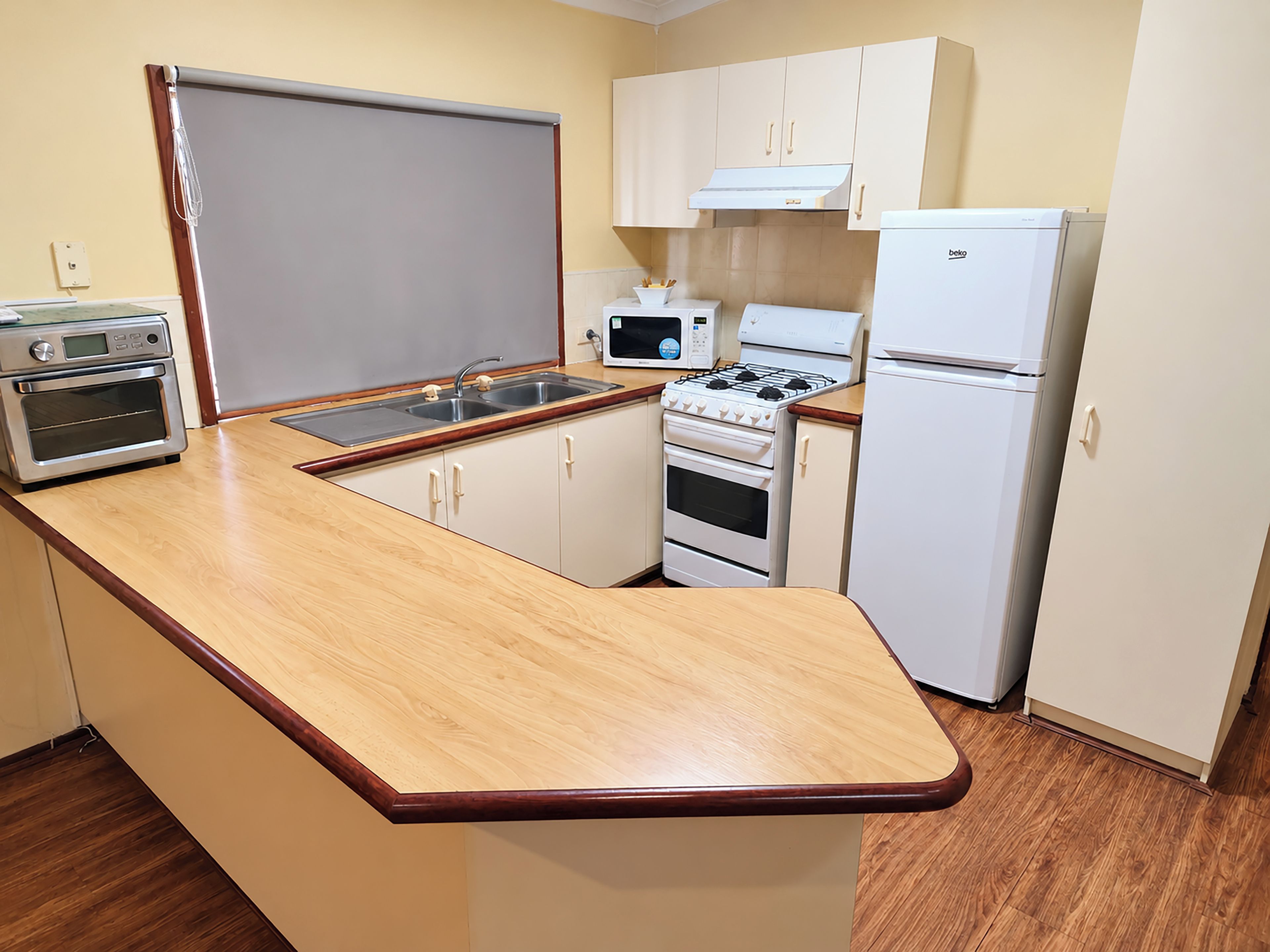 Una cocina compacta con horno integrado, microondas, estufa y refrigerador.