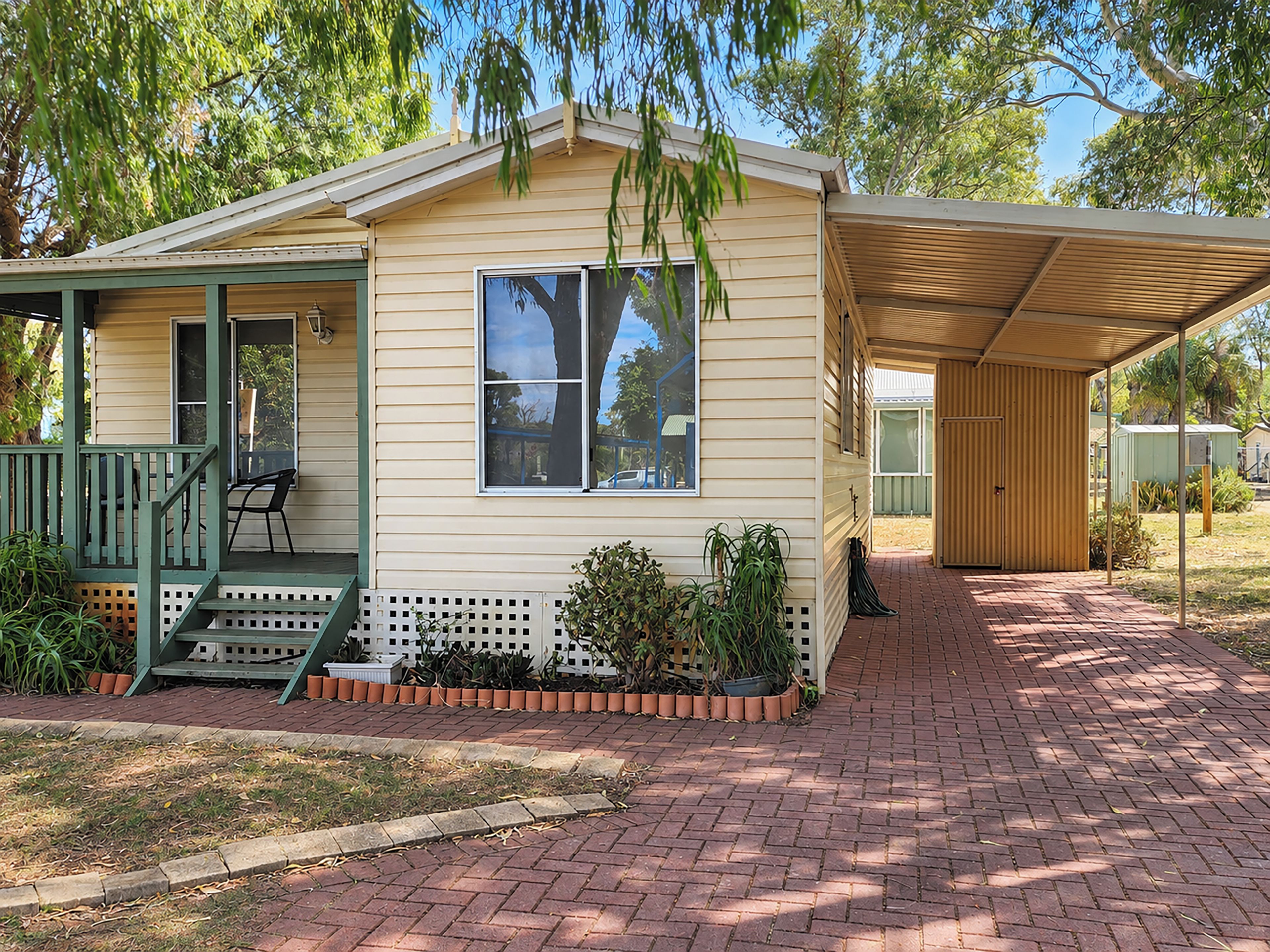 A single-story house with a porch, a covered patio, and a brick pathway.