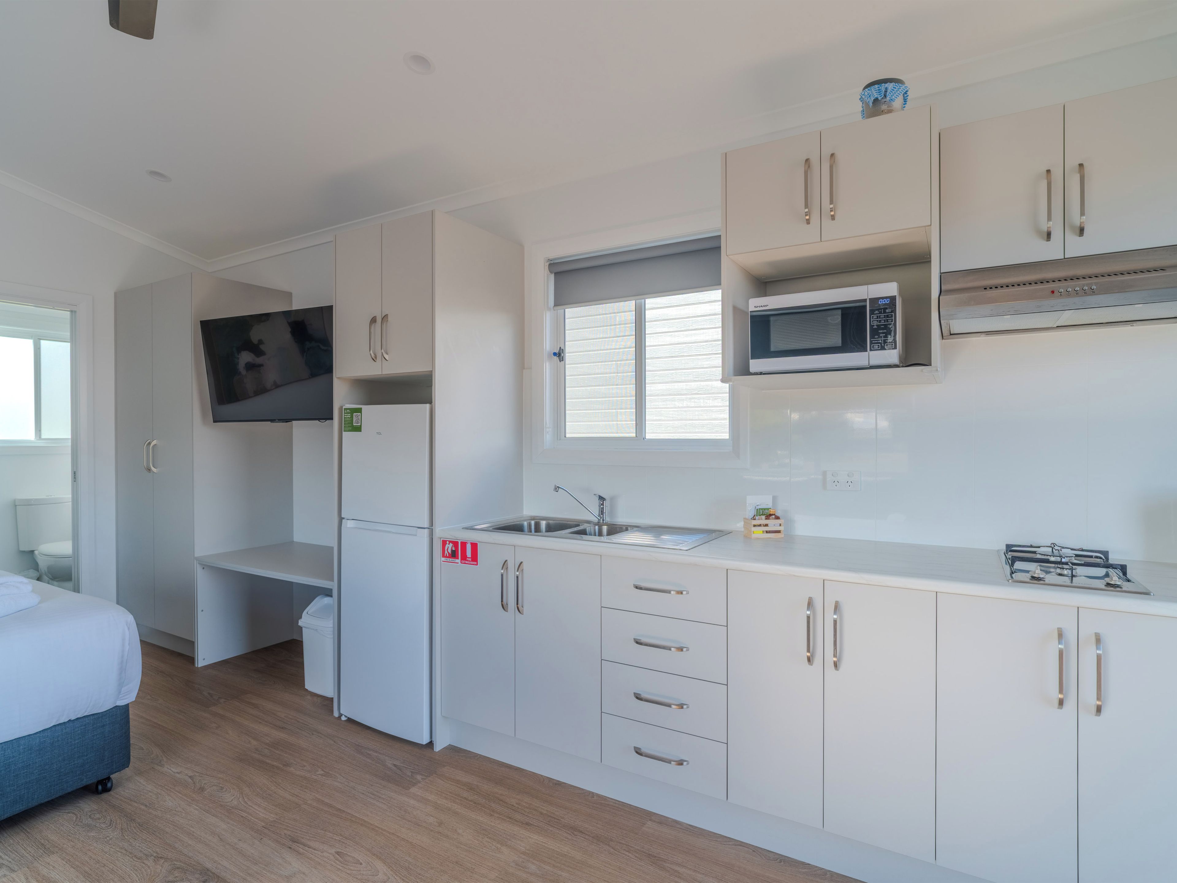 A modern kitchen with white cabinets, a microwave, and a sink.