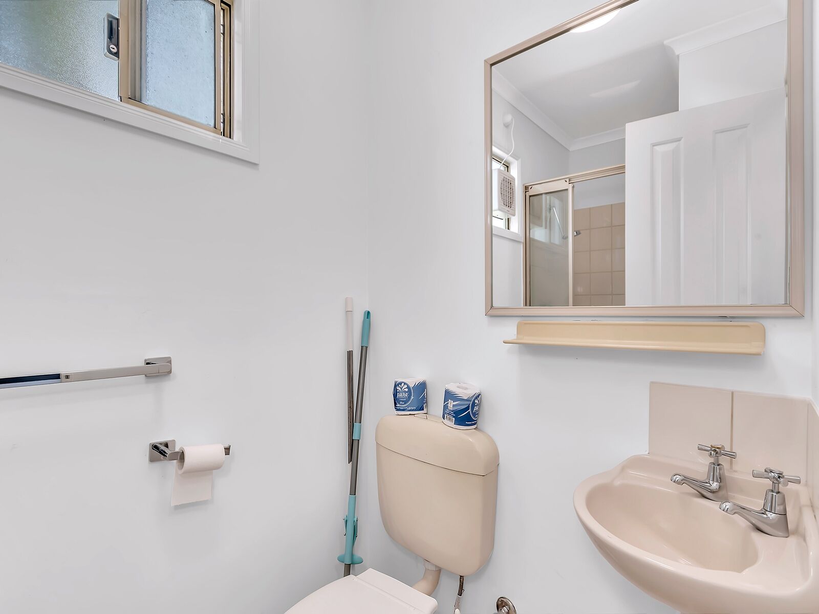 Un bagno con il water, un lavandino, uno specchio e una finestra.