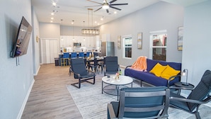 A modern living room with a sofa, chairs, and a coffee table. There is a kitchen in the background with a dining area. - Seize the Moment 4BR 3BA Gem w Downtown Views (San Antonio)