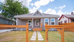 A residential house with a grey exterior, a front porch, and a fenced backyard. - Seize the Moment 4BR 3BA Gem w Downtown Views (San Antonio)
