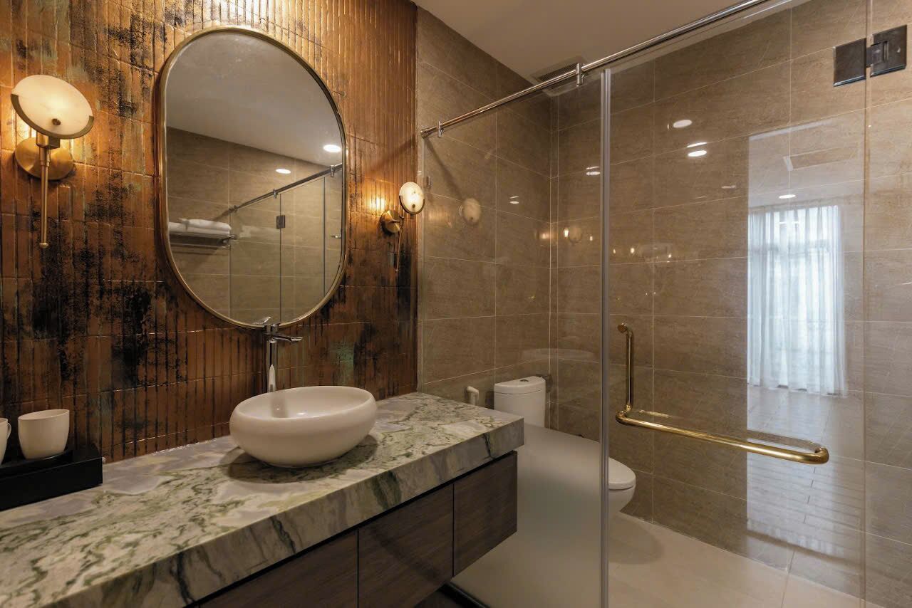 A modern bathroom with a marble sink, a large mirror, and a glass-enclosed shower area.