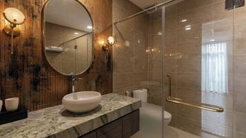 A modern bathroom with a marble sink, a large mirror, and a glass-enclosed shower area.