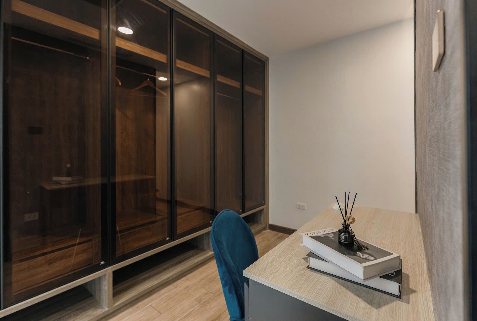 A modern room with a large sliding glass door closet, a small table with a book and a candle, and a blue chair.