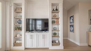 A modern kitchen with white cabinetry, wooden shelves, and a central island.