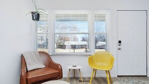 A room with a brown leather sofa, a small white table, a yellow chair, and a white door. - Established listing! KSU Sports & Events! Great location for all! 4bd 2ba (Manhattan)