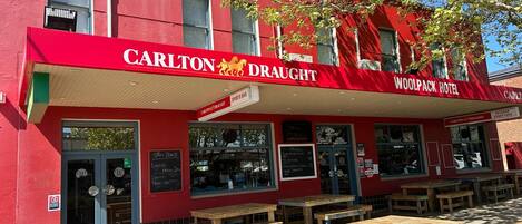 A red building with a sign for the Carlton Draught Sports Bar and Woolpack Hotel.