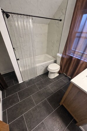 A bathroom with a shower, toilet, and sink.
