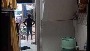 A narrow hallway with a tiled floor, a green water dispenser, and a person standing at the end. - Golden View Dormitory (Mumbai)