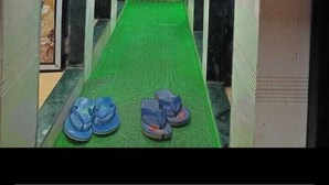 A narrow hallway with a green carpet, decorative walls, and a fan on the ceiling. - Golden View Dormitory (Mumbai)