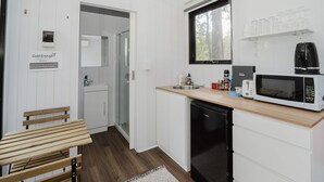 Pieni, käytännöllinen keittiö, jossa on valkoiset kaapit, mikroaaltouuni, leivänpaahdin ja pesuallas.