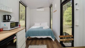 Ein kleines Schlafzimmer mit einem Bett, einer Mikrowelle, einer Kaffeemaschine und einem kleinen Kühlschrank.