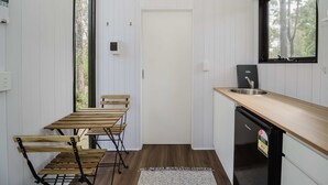 Eine kleine Küche mit Holztisch und -stühlen, einem eingebauten Spülbecken und einem Kühlschrank.