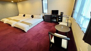 Habitación de hotel con dos camas, un escritorio con computadora, una silla, una mesita y una ventana con cortinas.
