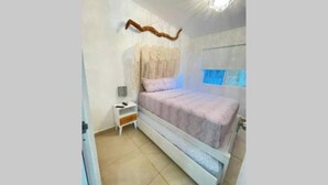 Quarto com cama, mesa de cabeceira e luminária na parede.
