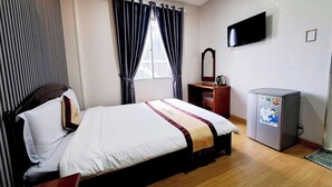 Una habitación de hotel con cama, televisor, escritorio y cafetera.