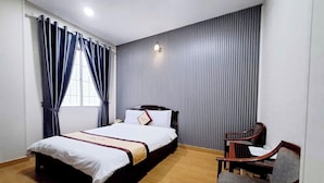 Una habitación de hotel con cama, una silla, una mesita de noche y una ventana con cortinas.