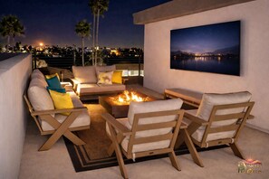 A rooftop terrace with a fire pit, seating area, and a large framed picture of a night sky over a body of water. - 🏜️🌵 Lotus N-Miller Rd 🌵🏜️ (Scottsdale)